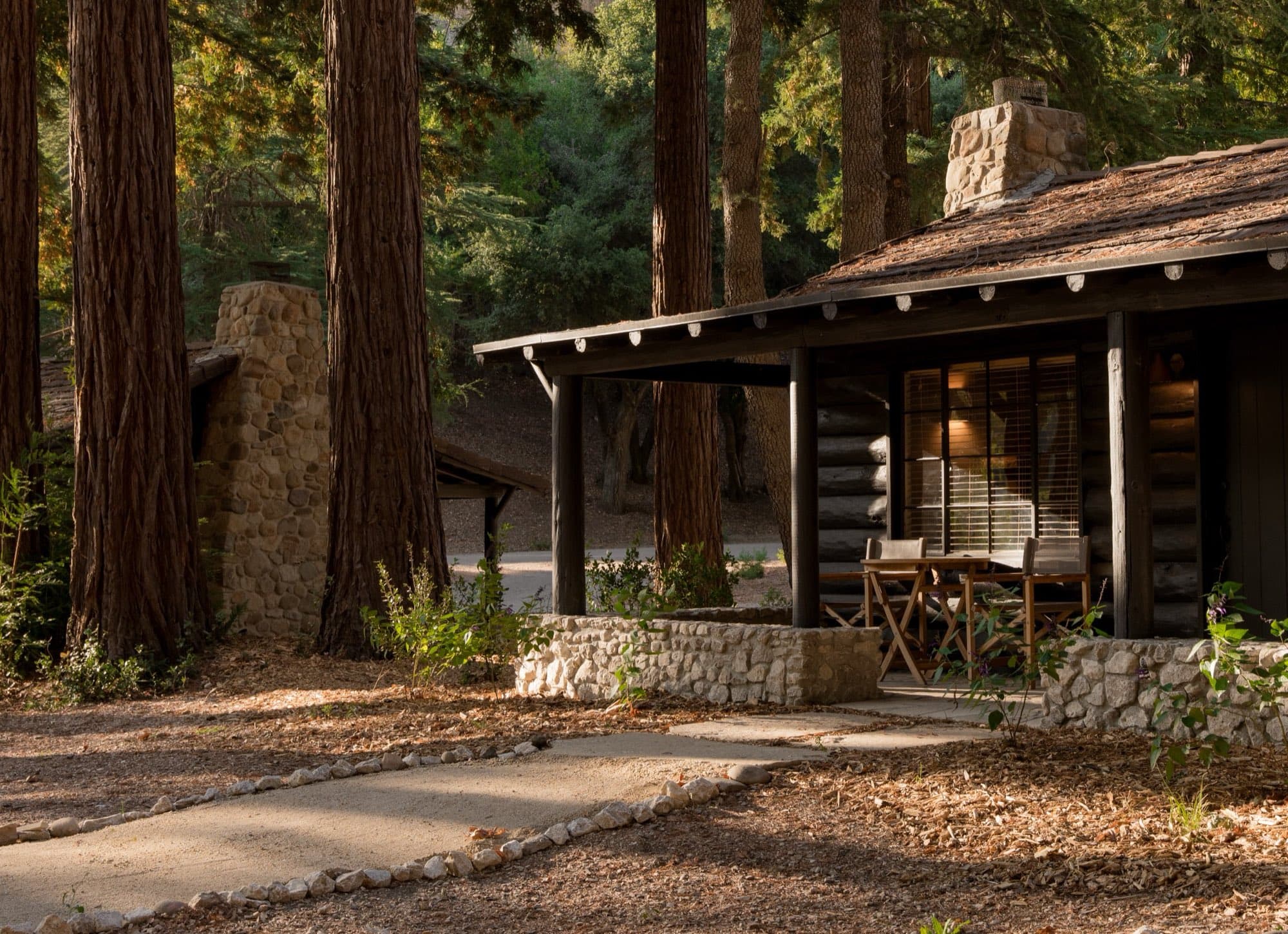 A cabin lit at dusk under the redwoods